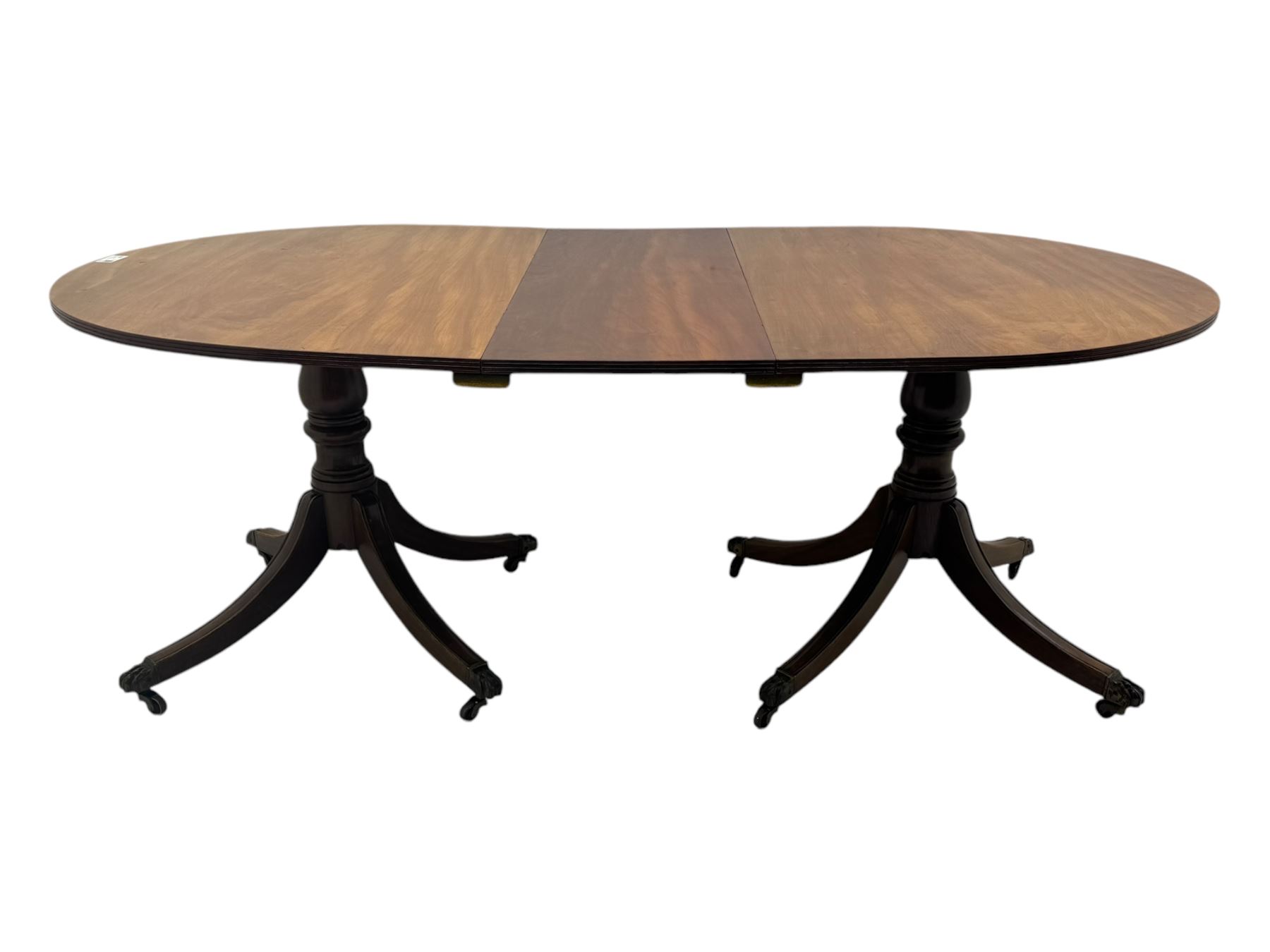 Georgian design mahogany twin pedestal dining table, oval top with reeded edge, single additional leaf, on turned pedestal with four out splayed supports, cast brass hairy paw castors 