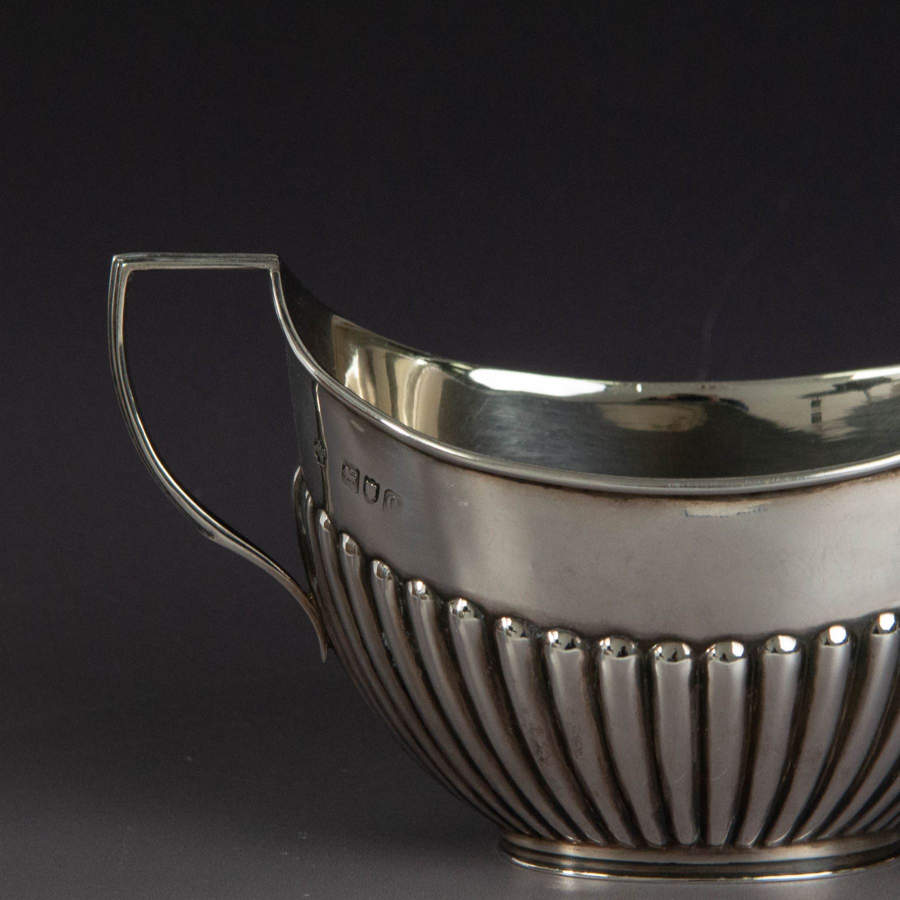 Victorian silver two piece bachelors tea service, comprising teapot and milk jug, of oval part fluted form, the teapot with ebonised wooden handle and finial, hallmarked Josiah Williams & Co, London 1895, together with a silver milk jug and open sucrier, of similar form, hallmarked William Hutton & Sons, London 1898