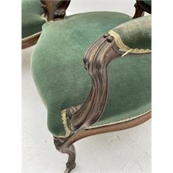 Set three Victorian rosewood drawing room open armchairs, shaped and moulded frames carved with scrolls, the arms with scrolled terminals and shaped foliate carved supports, upholstered in green velvet, serpentine sprung seats, the cabriole supports carved with flower heads terminating at castors