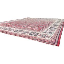 Persian red ground carpet, the field decorated with large floral Herati motifs, ivory ground border decorated with floral panels and stylised plant motifs, within scrolling guard bands 
