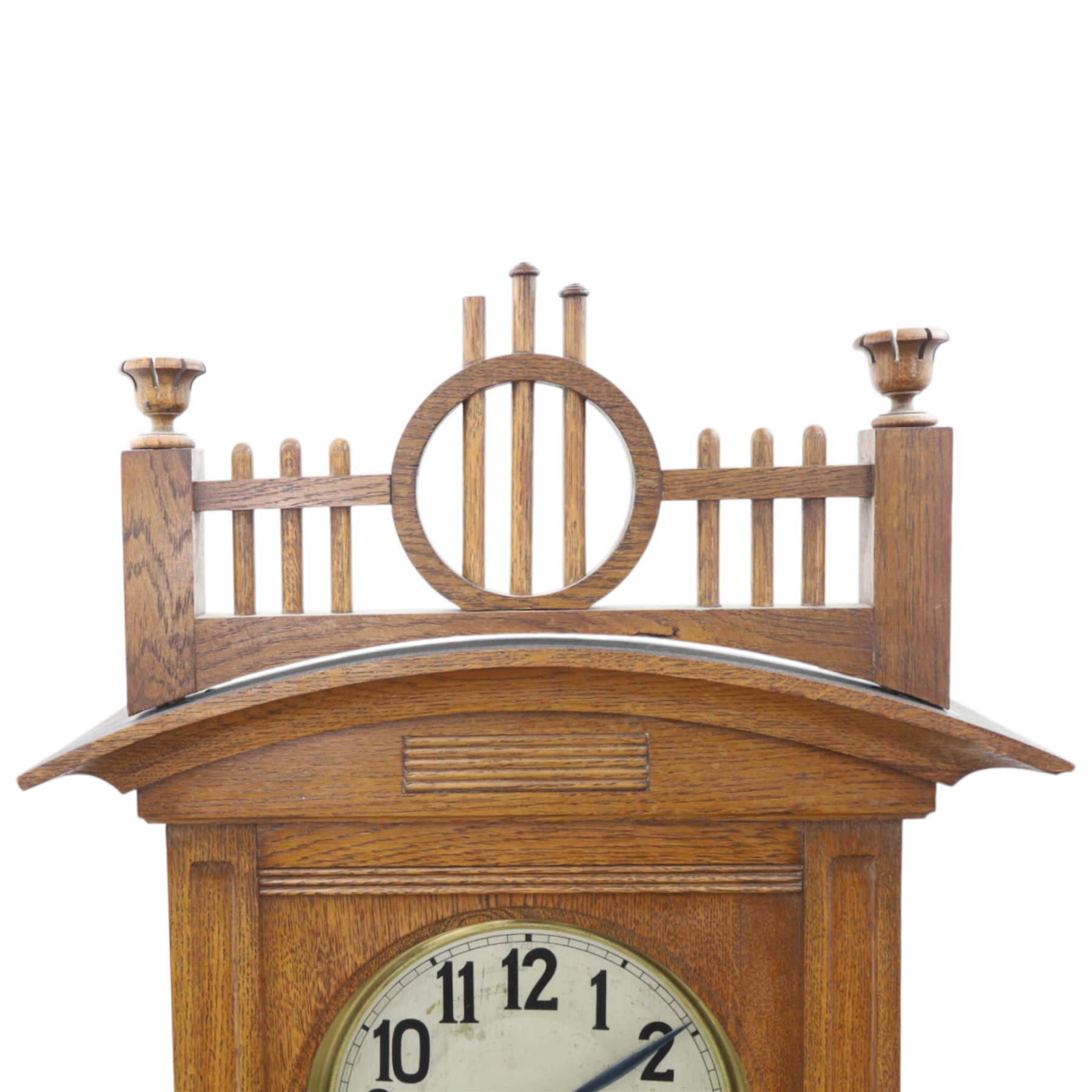 German-Art Deco 8-day longcase clock in an oak case, with a curved top and open fence work pediment, with reeded decoration and a fully glazed case door with a rectangular brass open work panel, on a tall rectangular plinth with a period  carved motif, circular slivered dial with Arabic numerals and spade hands, two train HAC (Hamburg and American Clock Company) weight driven movement, sounding the hours and half-hours on a coiled gong, with weights and pendulum.   