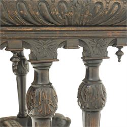 Victorian Jacobean Revival heavily carved oak centre table , rectangular top with canted corners and carved edge, fitted with single frieze drawer with central carved green-man handle with flanking gadrooning, the corners with lion masks, raised on fluted supports terminating to splayed stylised dolphin feet with castors, united by stretcher