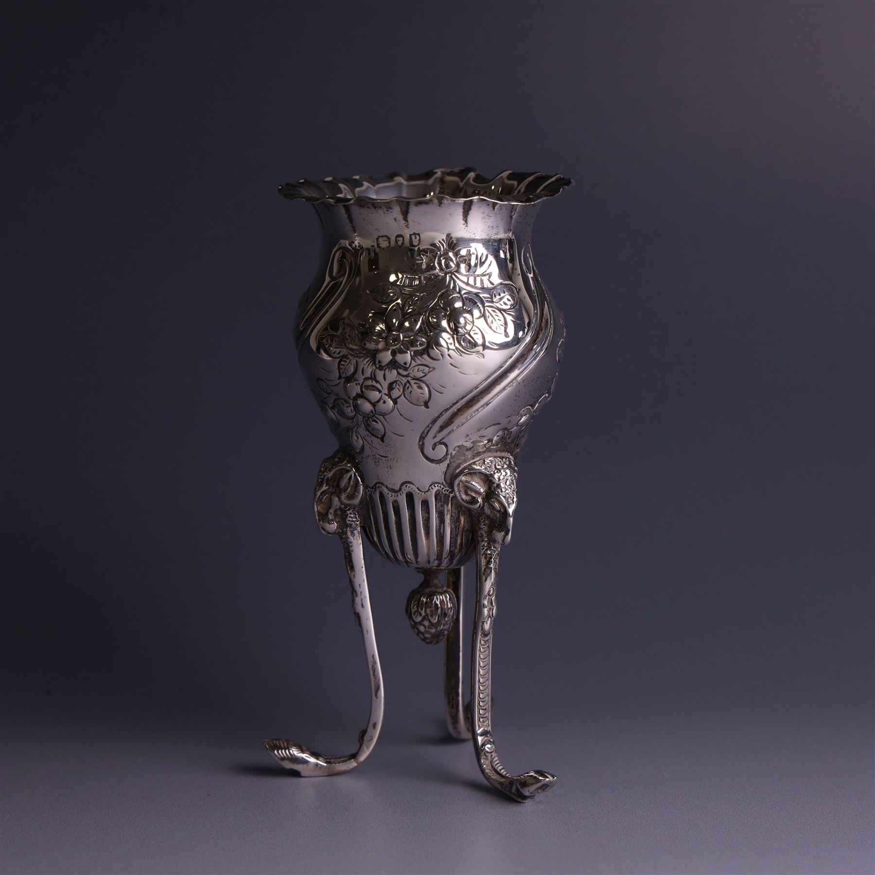 Late Victorian silver vase, of baluster form with fluted rim, the body with embossed floral decoration, upon three tall legs with ramshead mounts, hallmarked William Comyns & Sons, London 1890, H13.5cm