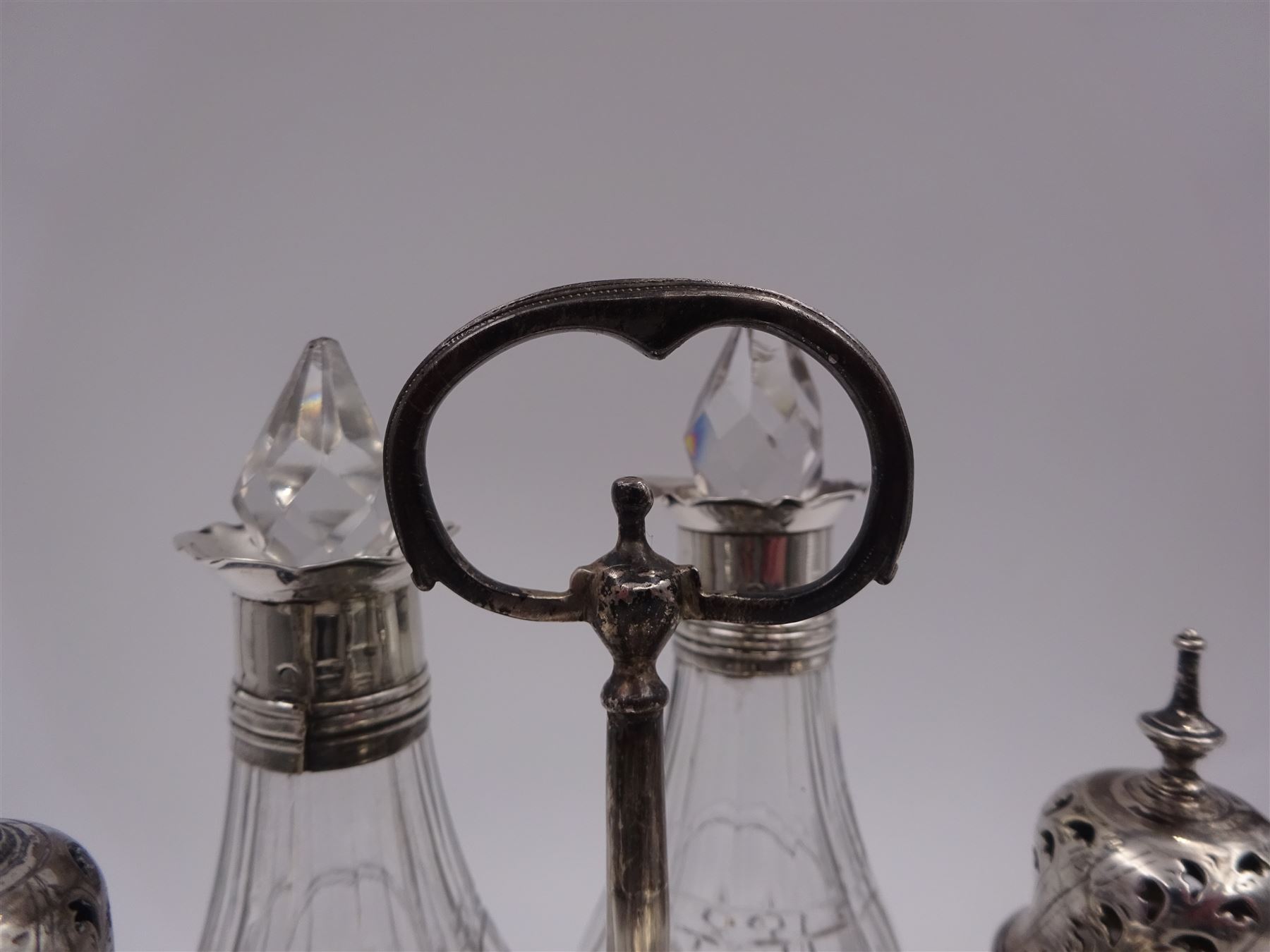Late 18th century silver cruet stand, of oval form, with pierced sides upon four bun feet, hallmarked to handle Hester Bateman, all other hallmarks indistinct, together with five matched silver mounted cut glass cruet bottles, including some later Victorian examples, hallmarks predominantly indistinct, stand H20cm