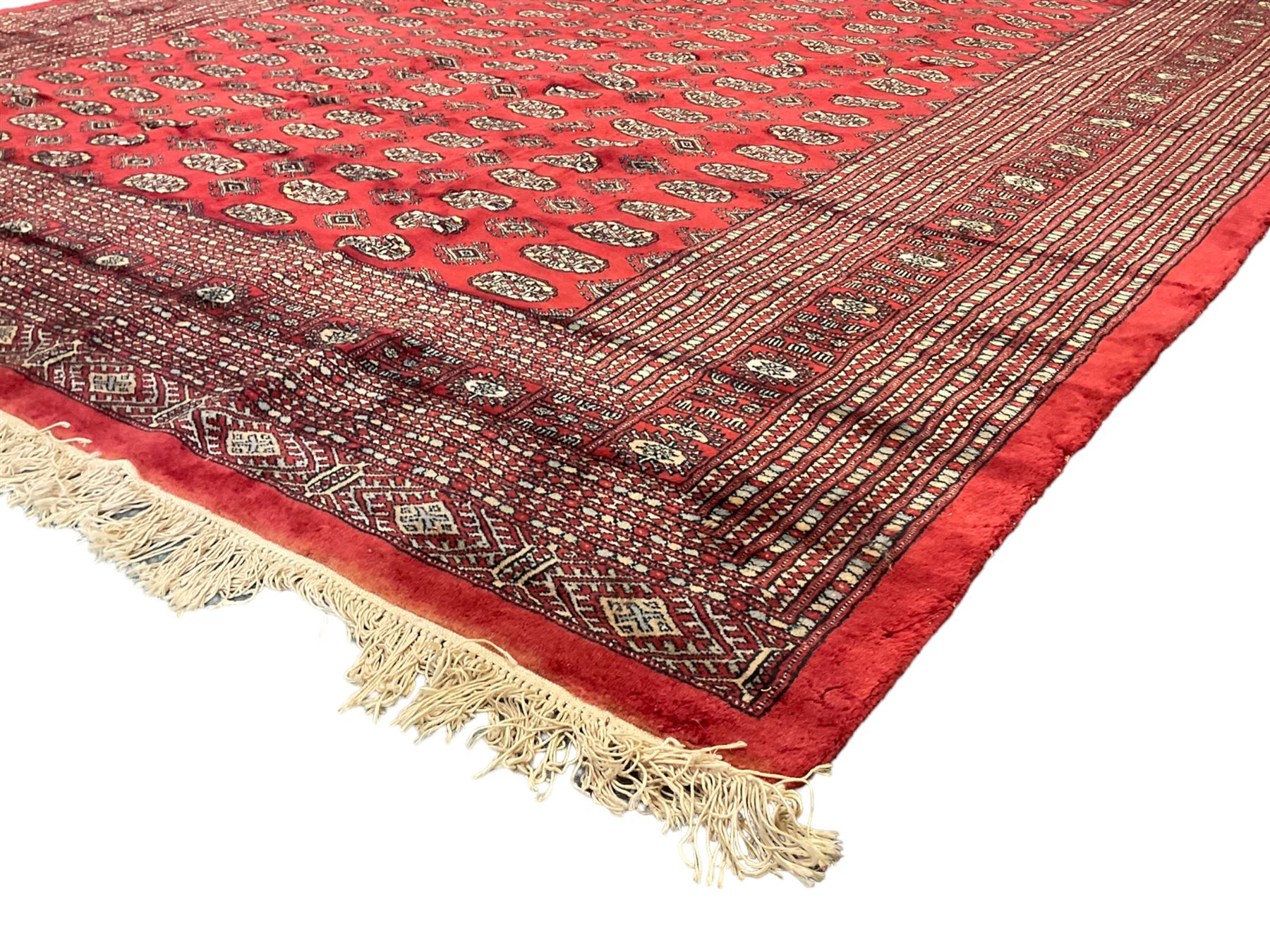 Persian Bokhara crimson ground carpet, the field decorated with repeating Gul motifs and lozenges, the multi-band geometric border with stylised plant motifs, two additional bands at the ends with geometric lozenges