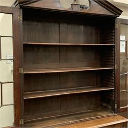 Georgian mahogany bookcase on press cupboard, moulded sloped arch pediment with central turned finial, two astragal glazed doors enclosing three adjustable shelves, moulded rectangular top over two fielded panelled doors, the interior fitted with three slides, on bracket feet, W129cm, H235cm, D50cm