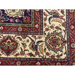 Northwest Persian signed Tabriz ivory ground carpet, central medallion with intricate floral motifs, the field and spandrels decorated with scrolling tendrils and palmettes, ivory main border with crimson and indigo floral decorations, surrounded by crimson guard bands