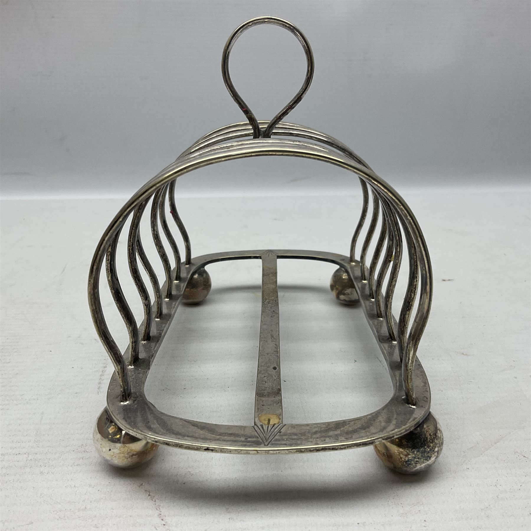 Silver plate seven bar toast rack, of curved form with central ring handle, upon bun feet, H13cm 