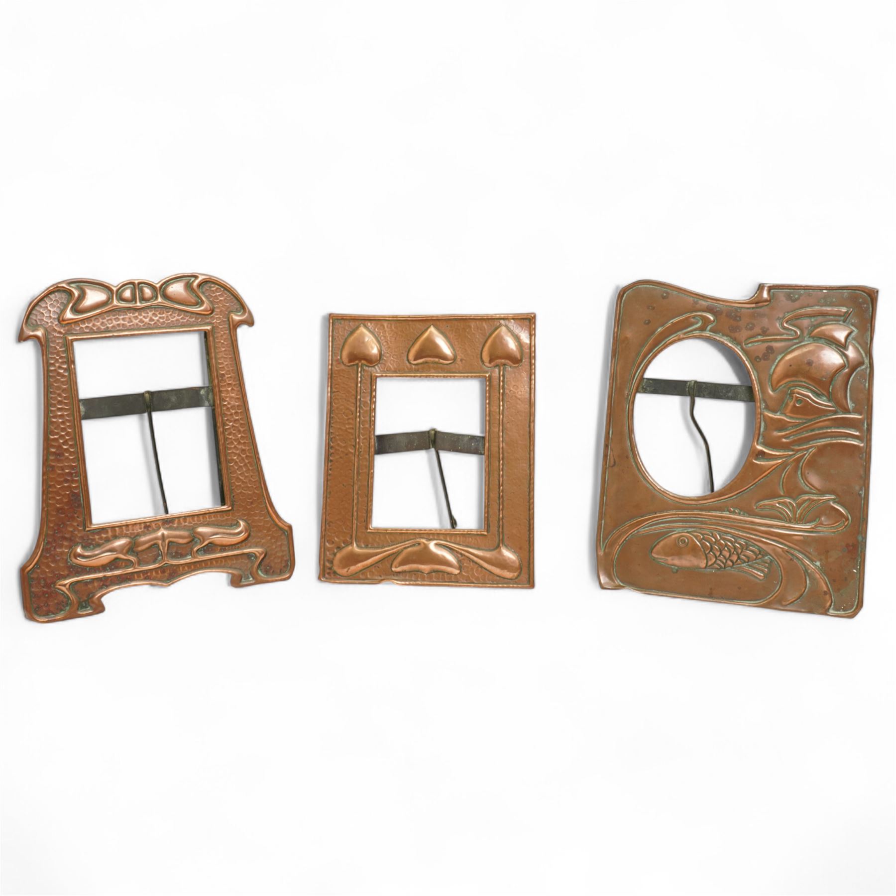 Newlyn type Arts and Crafts copper photograph frame decorated with a fish and galleon 24cm x 20cm with oval aperture and two other Newlyn style beaten copper frames (3)