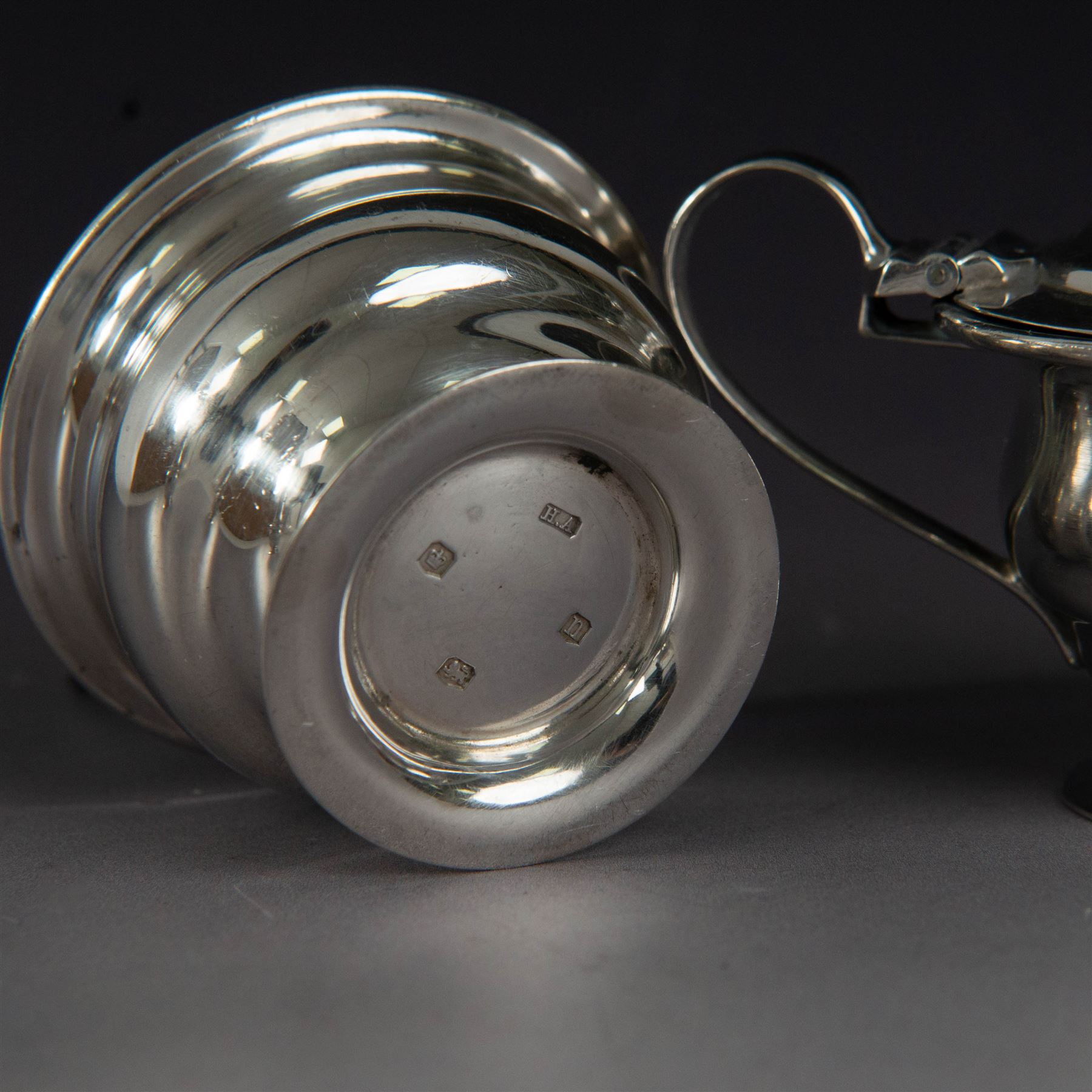 1930s silver three piece cruet set, comprising pepper shaker, open salt and mustard pot and cover, all of circular form upon circular spreading feet, hallmarked 	Atkin Brothers, Sheffield 1930, with two silver condiment spoons and blue glass liners