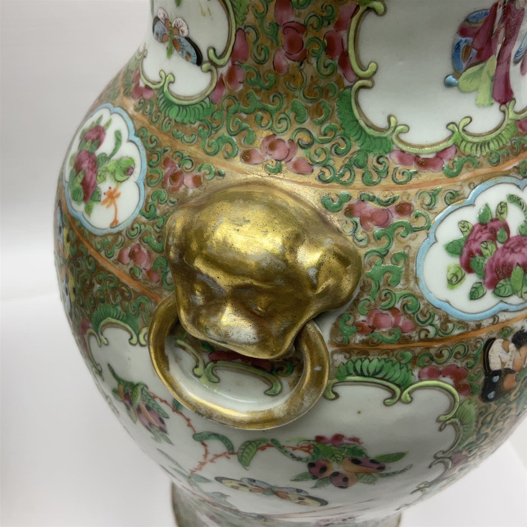 Pair of 19th century Chinese Famille Rose vases and covers, each of baluster form with twin gilt lion mask ring handles to shoulders, the flattened domed covers with gilt temple lion finials, each decorated with alternating reserves of bijin and attendants, and birds and butterflies amongst blossoming peonies, against a gilt ground profusely decorated with stylised scrolls, H32.5cm