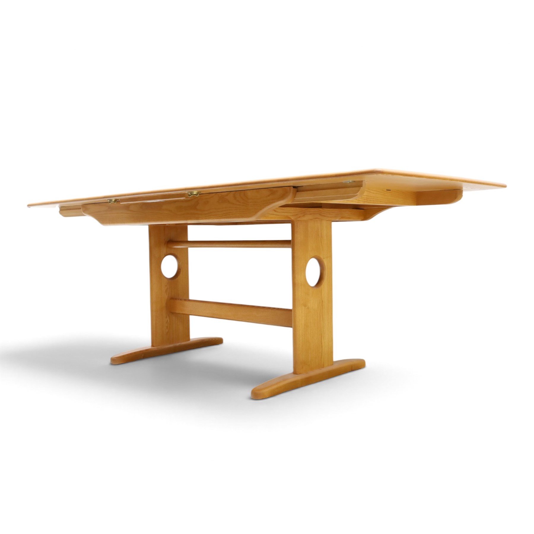 Ercol - 'Windsor' ash medium extending dining table, with stowed fold over leaf extending to 200cm, shaped supports with roundel aperture, united by a stretcher