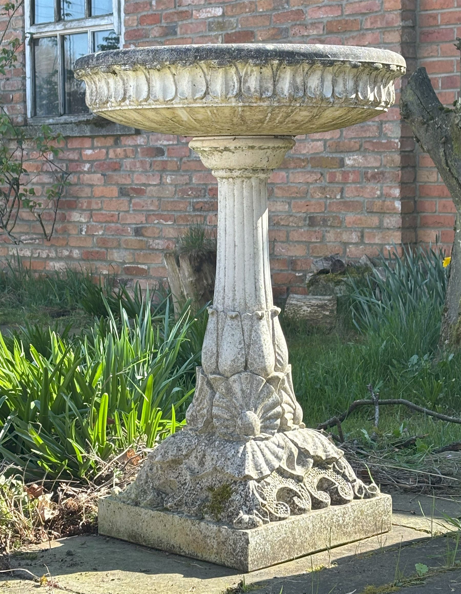 Reconstituted stone garden bird bath, the circular top with moulded waterleaf design on a pedestal decorated with floral motifs. H87cm, D59cm. - COLLECTION BY APPOINTMENT FROM: The White House, Thirsk Road, Easingwold, York, YO61 3NF - CALL 01723 507111 TO ARRANGE