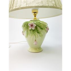 A pair of Italian ceramic lamps, of baluster form, the light green glaze detailed with pink flowers, with pleated light green shades, overall H45cm.