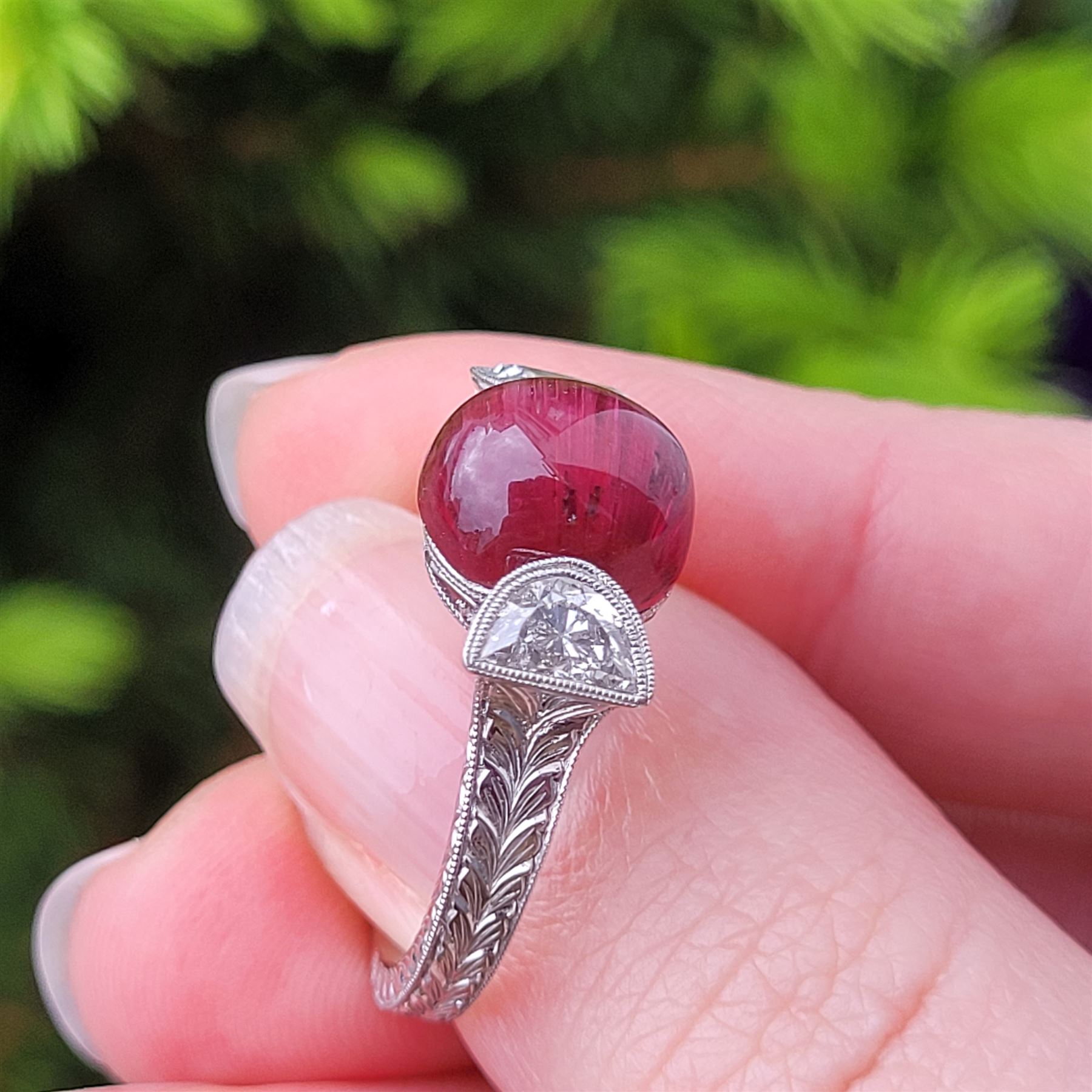 18ct white gold pink tourmaline and diamond ring, single oval cabochon cut tourmaline of approx 4.75 carat, set with a half moon cut diamond either side, to engraved laurel leaf design shoulders