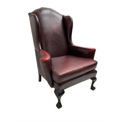 Georgian style wingback armchair, upholstered in red leather with stud work, curved arms with scrolled terminals, on ball and claw front feet