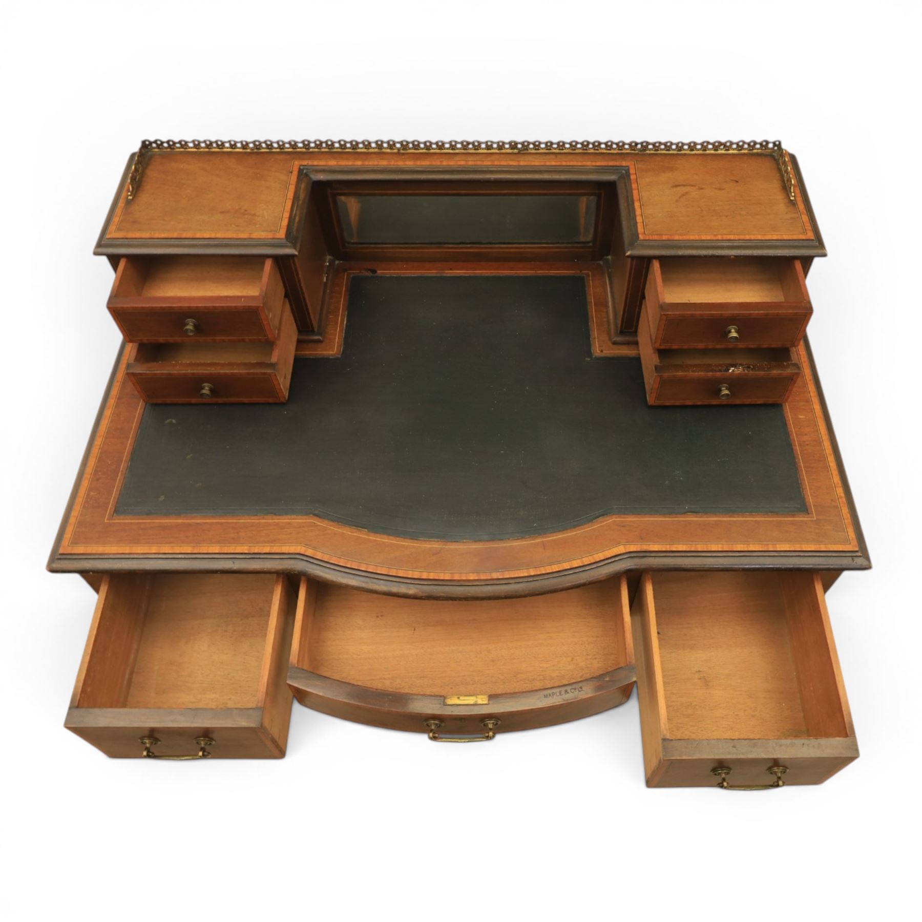 Maple & Co - Edwardian mahogany inlaid writing desk, the superstructure with pierced brass gallery, above an inset mirror and two short drawers, inset leather writing surface, bow fronted with crossbanded drawers and brass swan neck handles, square tapering supports terminating in castors 