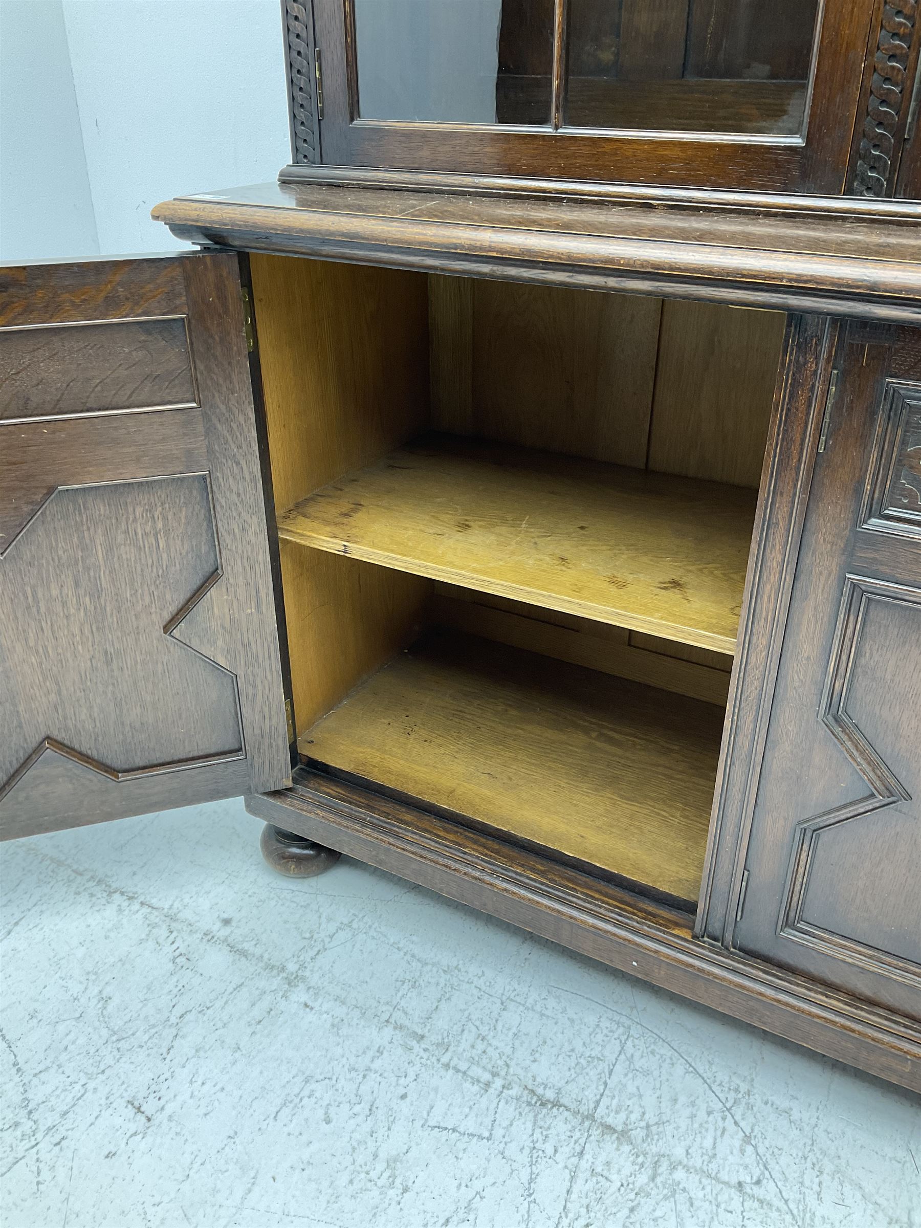 Waring and Gillow - oak bookcase on cupboard, projecting cornice over arcade frieze, guilloche upright decoration, the top section enclosed by three astragal glazed doors, the lower section enclosed by three geometric panelled doors with blind fretwork decoration, on turned feet
