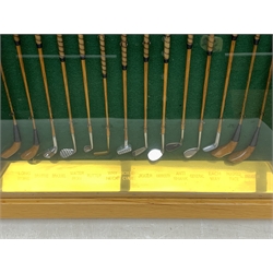 Modern handcrafted miniature set of fourteen 19th century style golf clubs by P.D. Rushworth dated 2000, each with turned wooden shaft and leather grip, comprising four woods including long nose driver, brassie and hooked face, and ten other metal head clubs including jigger, water iron, rut iron, anti-shank iron, wryneck iron, mammoth iron, Schenectady putter, etc., displayed in a baise lined architectural style oak case with hinged door, annotated brass strip and maker's plaque, longest club 28cm, case W52cm, H44cm