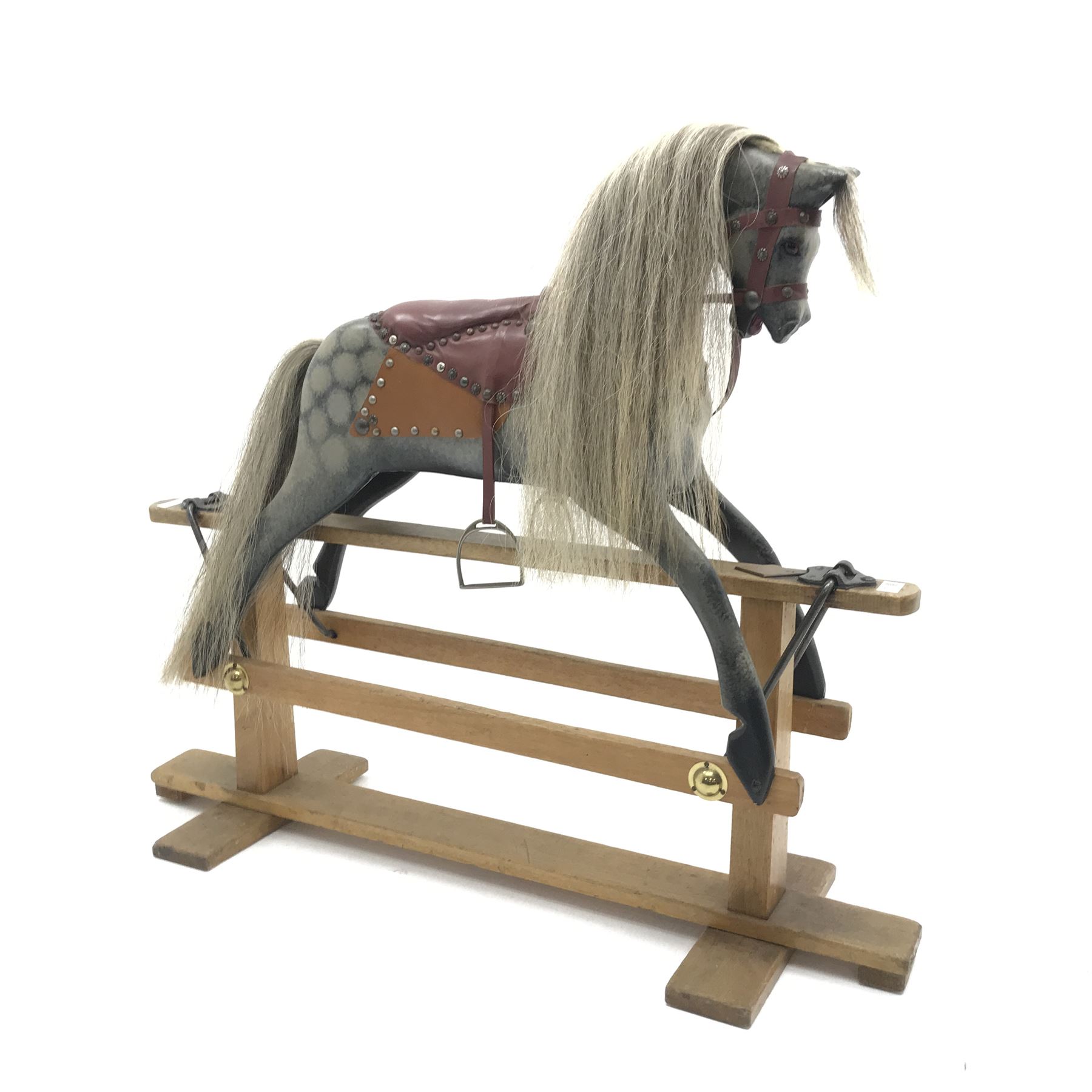 Early 20th century dapple grey rocking horse, leather rein and saddle with stirrups on trestle base