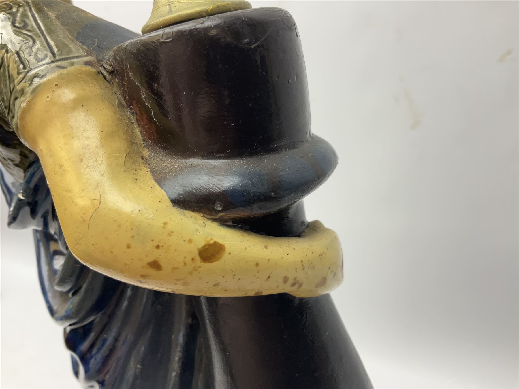 Composite table lamp modelled as a Roman Emperor donning blue robes, upon quatrefoil base modelled with rams heads and winged cherubs, H56cm excl fitting