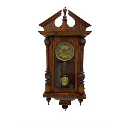 German early 20th century wall clock in a mahogany case with an architectural pediment and turned finial, with applied carving and pendant finials, fully glazed door with a visible gridiron pendulum, eight-day spring driven striking movement striking the hours on a gong, dial with Roman numerals to the chapter and a gilt repoussé centre.   

