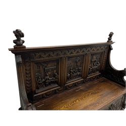 19th century heavily carved oak settle, the moulded upper rail over triangular foliage carved frieze, three Flemish style carved panels depicting tavern scenes, acanthus carved uprights terminating to lion carved arms, hinged box seat, the panelled front carved with lion masks and extending scrolled acanthus leaves, on moulded skirt base