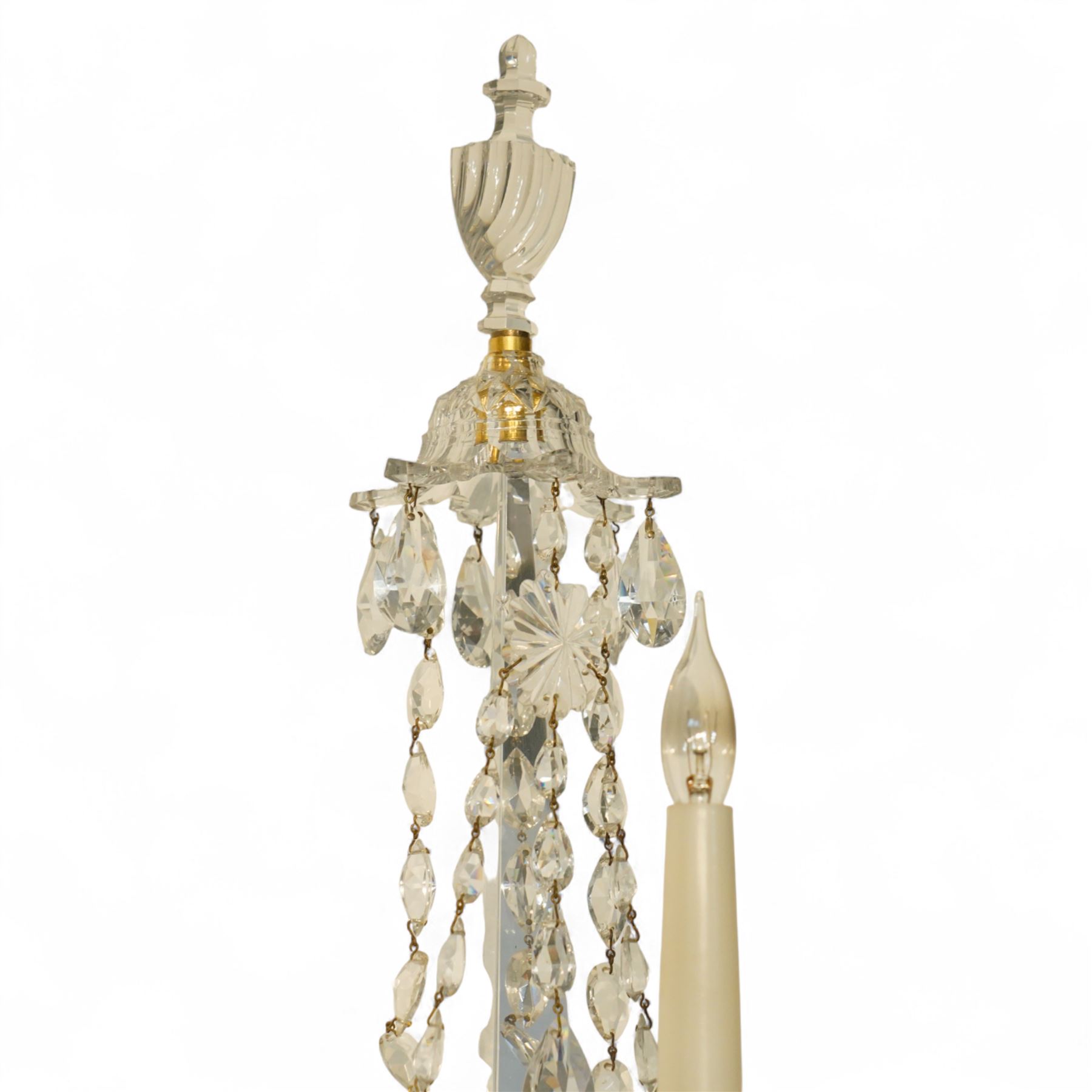 Pair of George III ormolu and cut-glass wall-lights, each with a tall central urn-shaped finial above a series of faceted glass spires and scrolled branches, the ormolu-mounted nozzles and drip pans hung with festoons of cut-glass drops and pear-shaped pendants, the lower section centred by a pineapple finial, wired for electricity