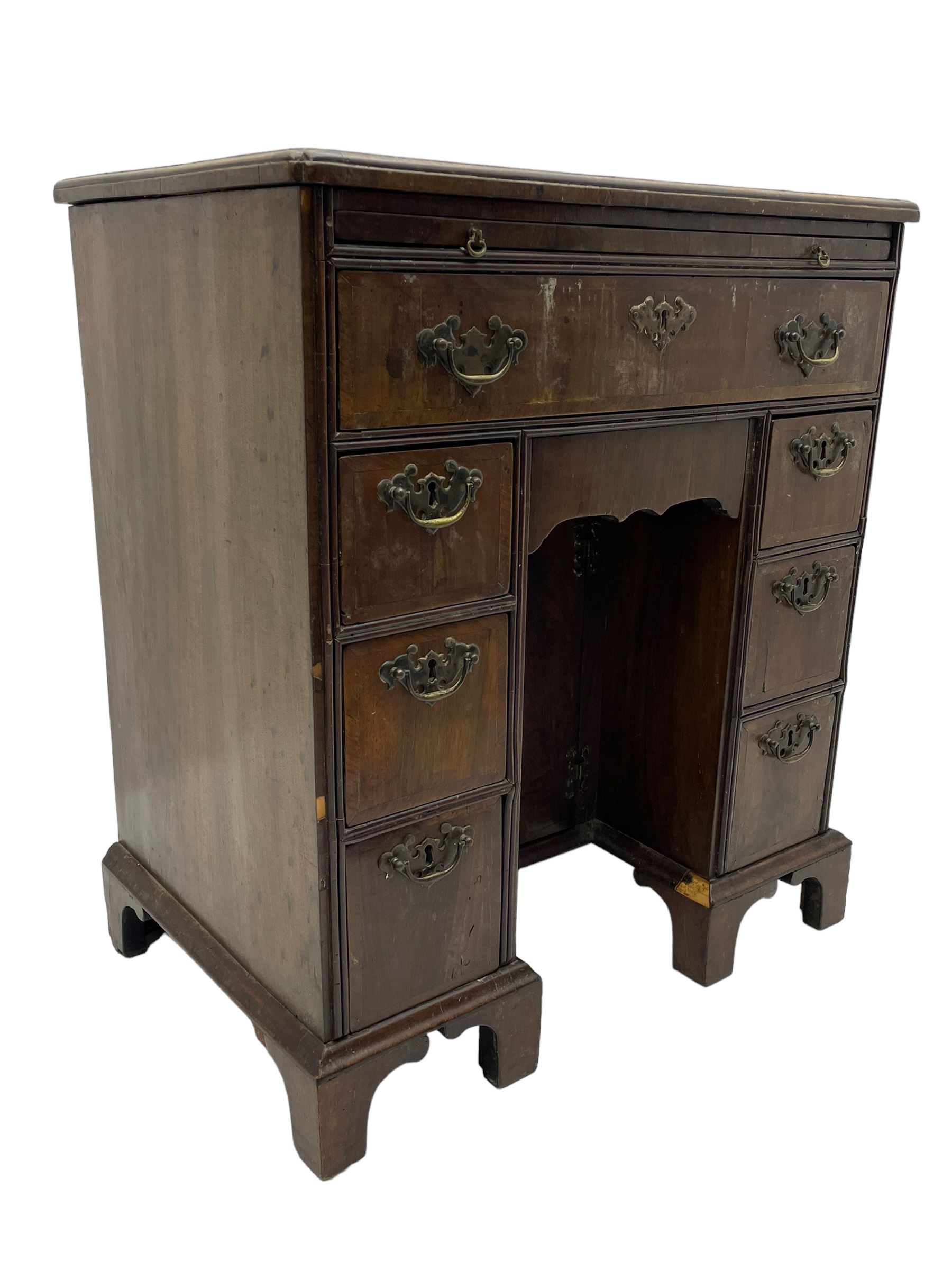Georgian walnut kneehole desk, moulded rectangular top with book-matched veneers within crossbanding, fitted with slide over one long drawer, frieze drawer, six small drawers and recessed cupboard, raised on bracket feet