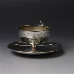 German silver cup and saucer, both with engraved foliate decoration, stamped 800, the saucer with crescent and crown mark
