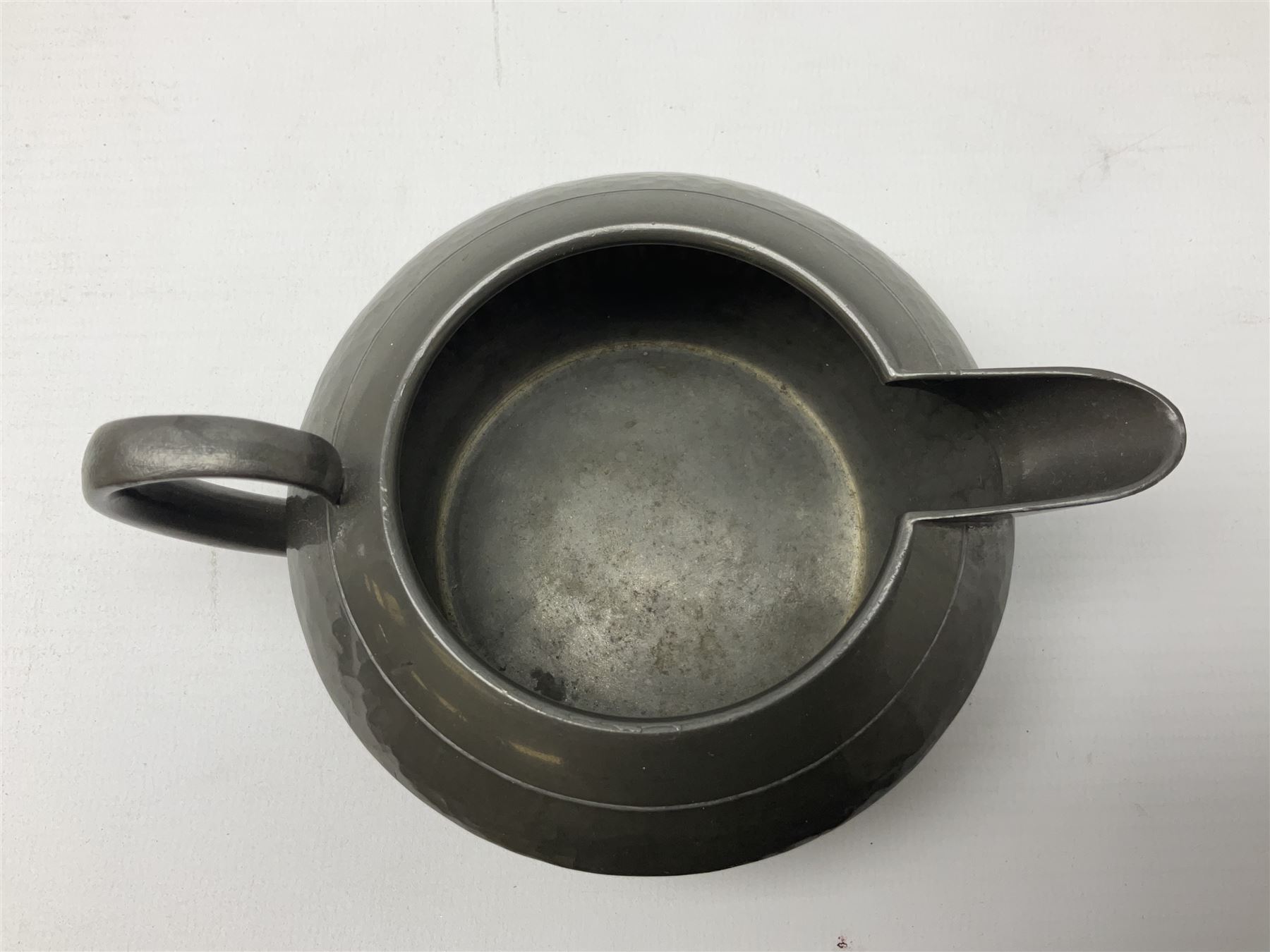 Liberty & Co Tudric pewter three piece tea service, comprising teapot with woven reed handle, twin handled open sucrier, and milk jug, each of squat form with planished finish, each impressed beneath Tudric Pewter Ware 01537 Made in England, together with a matched unmarked tray