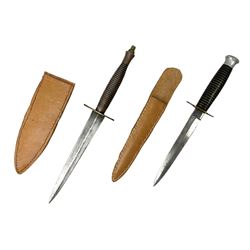 British Commando Fighting Knife, with 17cm unmarked double edged blade, brass cross-piece and coppered aluminium ribbed grip; in associated leather sheath L30.5cm overall; and another fighting knife with 15cm commando style blade, brass cross-piece, brass and black banded grip and aluminium pommel; in leather scabbard (2)