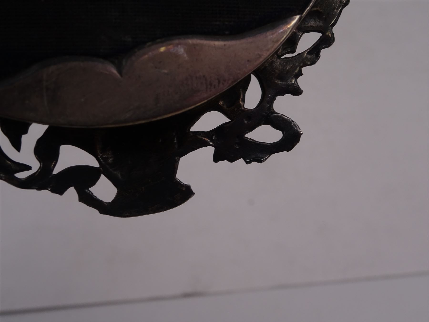 Continental silver miniature dressing table/wall mirror, of oval form with bevelled mirror plate, surrounded by a bead and dart rim, with pierced scrolling floral border with a standing cavalier to either side and the bust of a cavalier to the base, H17.7cm