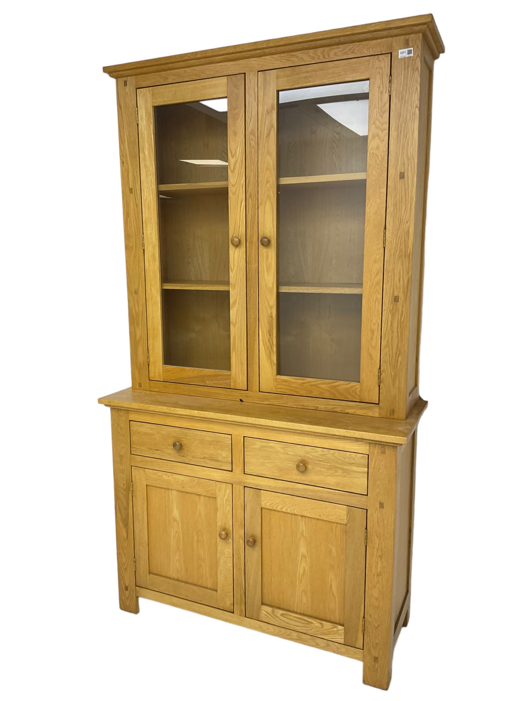 Contemporary light oak bookcase display cabinet, fitted with  two glazed doors enclosing two shelves, above two drawers and cupboards