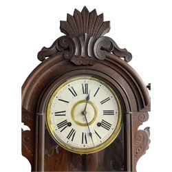 Ansonia-19th century American wall clock in a mahogany case with a carved pediment and base,  turned finials and carved side pieces, with a fully glazed door, dial with Roman numerals and visible pendulum, twin train spring driven movement striking the hours on a coiled gong. With key. 