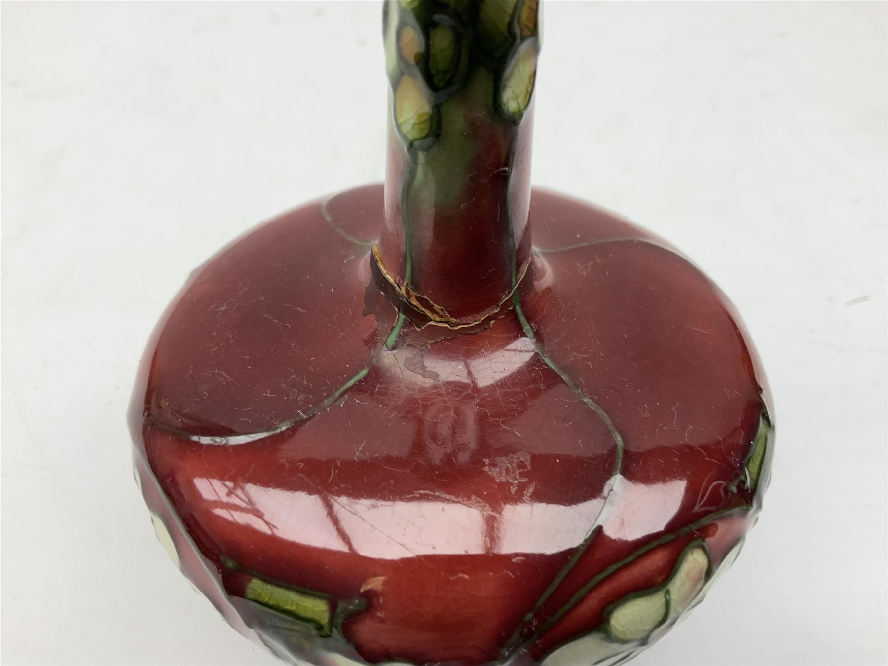 Three Minton Secessionist vases, with tube-lined stylised flower decoration, two upon a red ground and third upon a purple ground, all with printed mark to base 'Minton Ltd, No. 33', H13cm