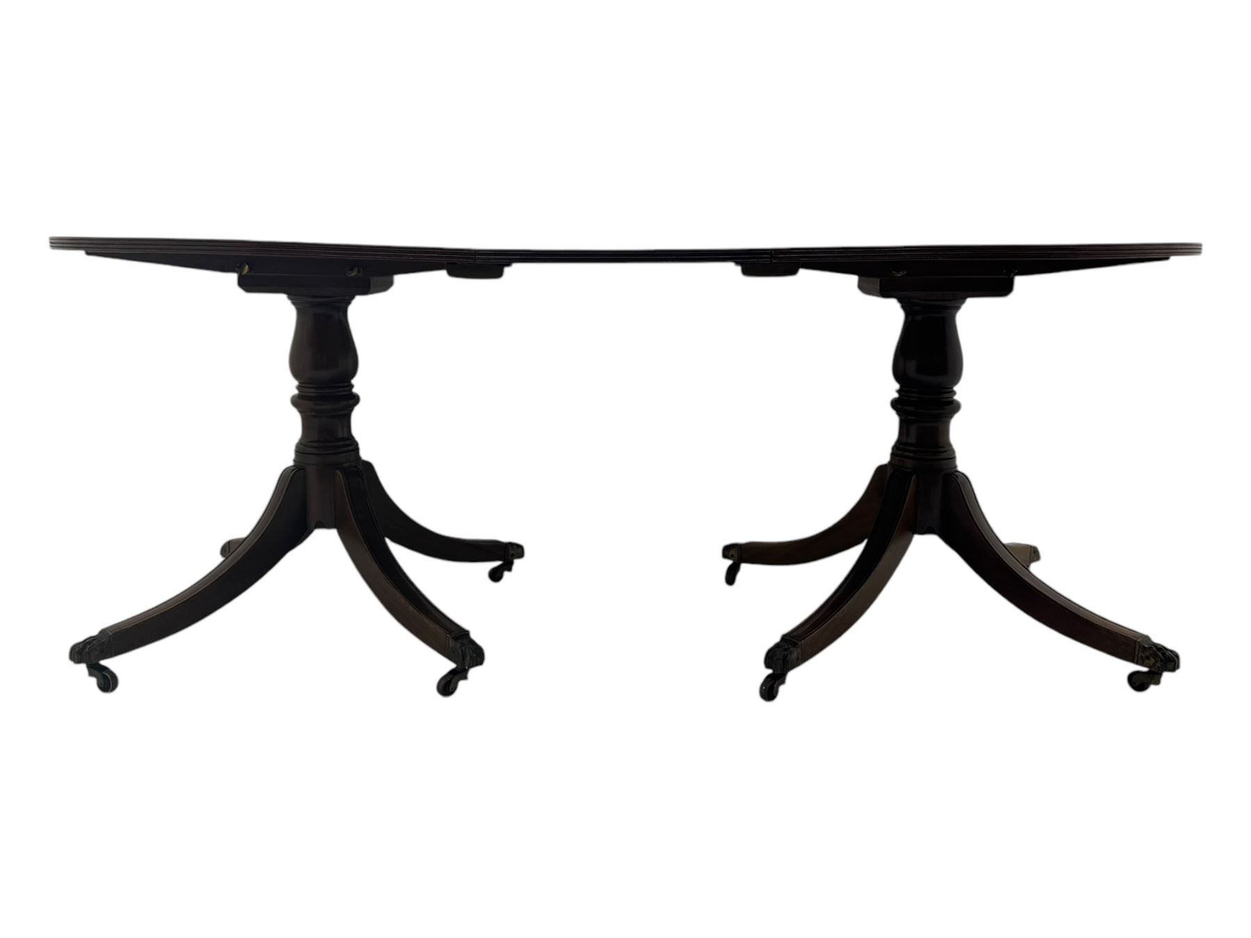 Georgian design mahogany twin pedestal dining table, oval top with reeded edge, single additional leaf, on turned pedestal with four out splayed supports, cast brass hairy paw castors 