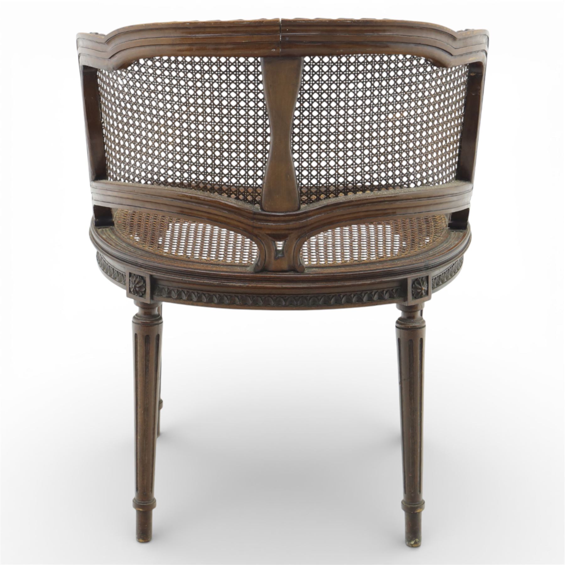 Late 19th century cane bergère armchair, the serpentine shaped back flowing into enclosed arms, the back and seat caned throughout, with carved detail to the crest and arm terminals, on turned legs