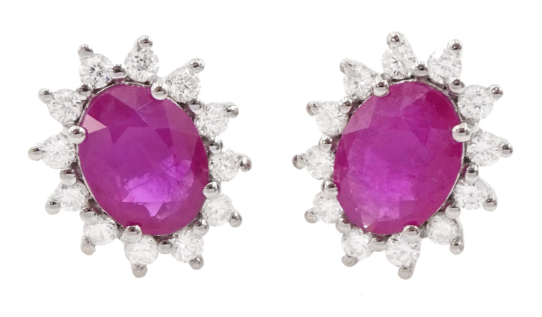 Pair of 18ct white gold ruby and diamond cluster earrings, each stud set with a single oval cut ruby and twelve round brilliant cut diamonds, stamped 750, total ruby weight approx 2.30 carat, total diamond weight approx 0.50 carat
