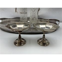 Pair of Mappin and Webb silver plate pierced pedestal bon bon dishes, together with other silver plate comprising teapot stand engraved with lion's head to centre, two cut glass claret jugs, two bottle coasters with acorn decoration, two open salts upon dolphin mounts, tea caddy, three piece cruet set and a large oval tray with pierced sides and upon four ball feet
