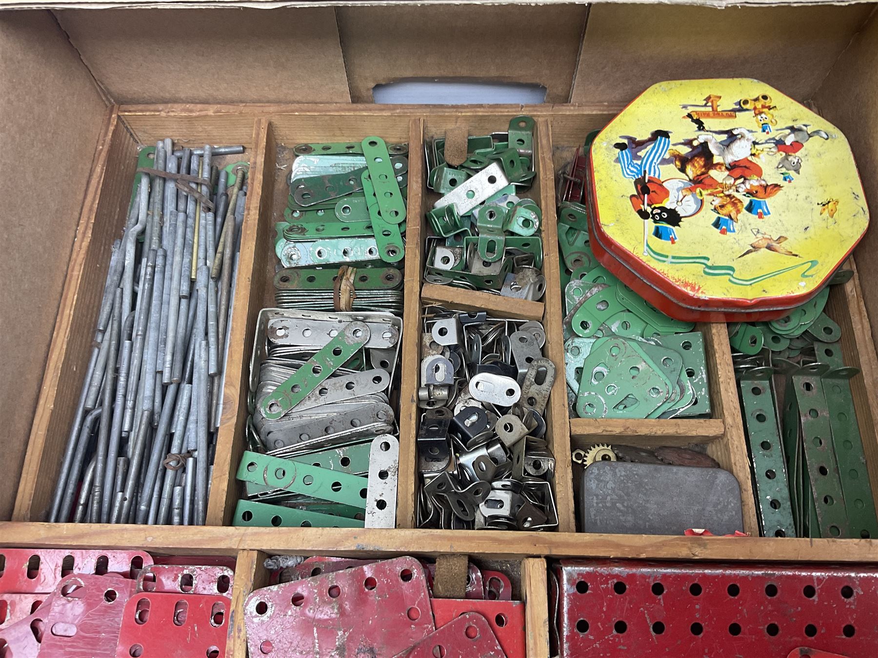 Meccano - large quantity of loose parts including various plates and strips, flanged plates, pulleys, axle rods and crank handles, wheels and tyres, gear wheels, brackets, nuts & bolts, various manuals; predominantly red and green; some in compartmentalised wooden trays