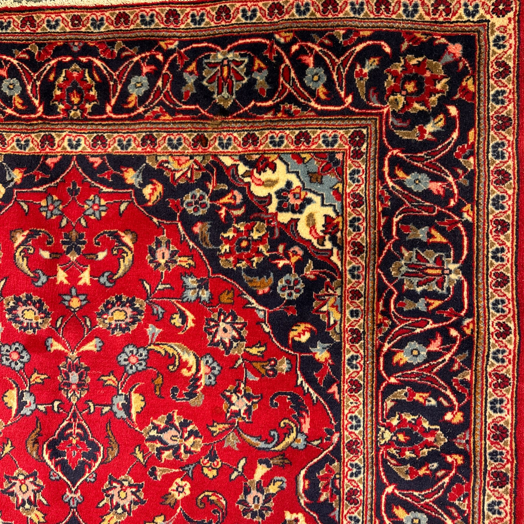 Central Persian Kashan rug, crimson ground with central medallion with  quarter medallions in each corner and decorated with floral sprays and palmettes, dark blue main border with repeating palmette and vine pattern   framed by small guard border with floral meanders 