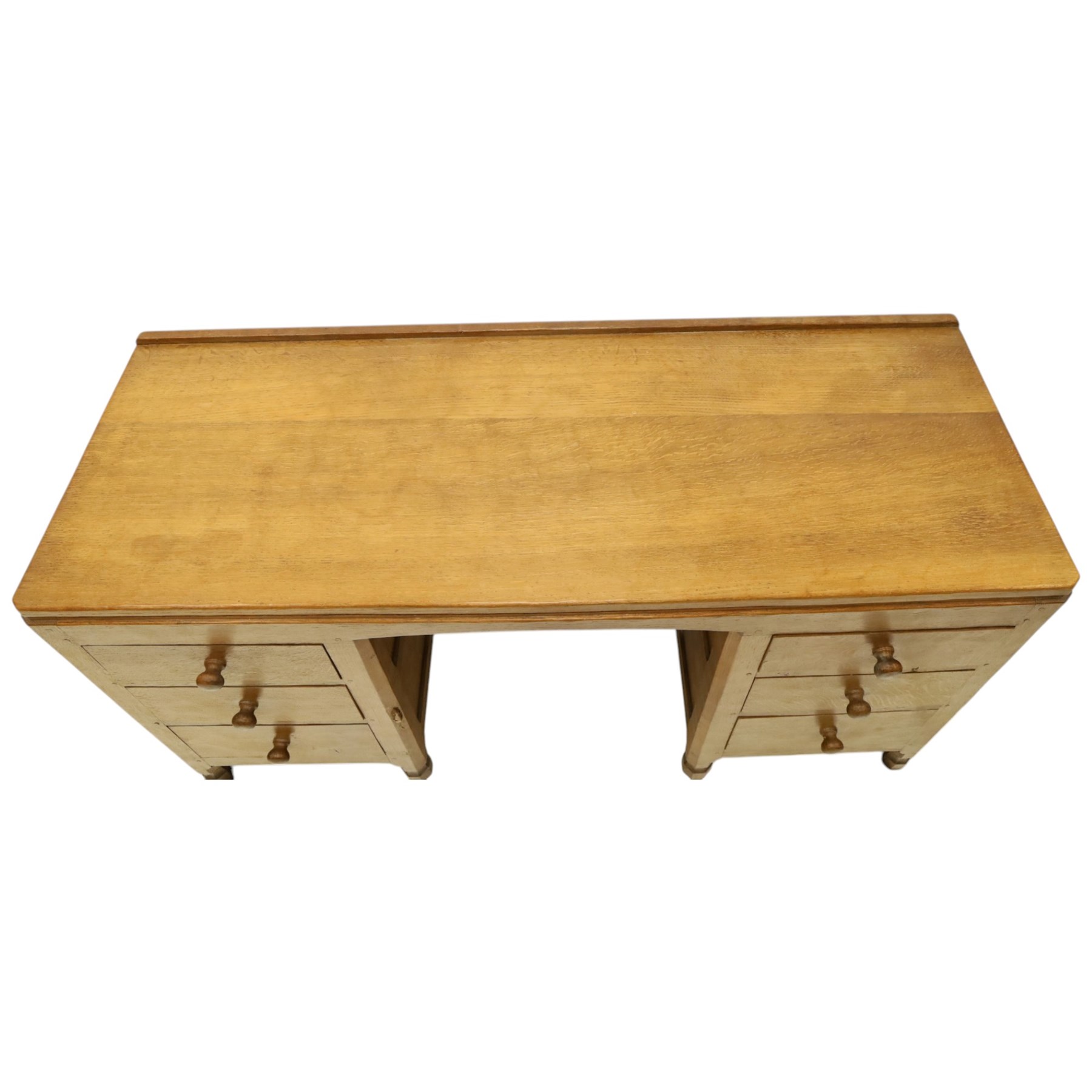 Mouseman - adzed oak kneehole dressing table or desk, the rectangular adzed top with raised back and canted corners, over an arched recessed kneehole flanked by three graduating drawers to each side with turned knob handles, raised on octagonal feet, with carved mouse signature, by the workshop of Robert Thompson of Kilburn