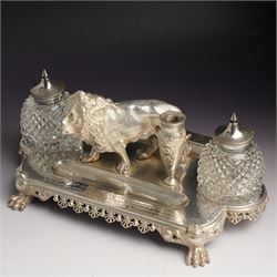 19th century Walker & Hall, silver plated inkstand, oblong and on four paw feet, the border decorated with pierced shell design, each side with a pen-rest, with two cut-glass bottles and central lion and urn finials, engraved to the front with an inscription, H15cm, L30cm