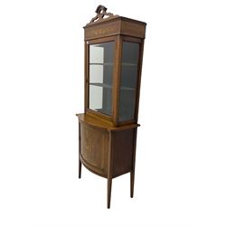 Edwardian inlaid mahogany display cabinet on cupboard, shaped pierced pediment over satinwood banded frieze inlaid with urn and scrolling foliage, enclosed by single glazed door, on bow front panelled cupboard inlaid with urn, square tapering supports