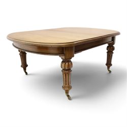 Large Victorian oak extending dining table, the rectangular top with rounded corners and moulded edge, plain frieze over large turned lobed and fluted supports terminating to brass cups and castors, with two additional leaves