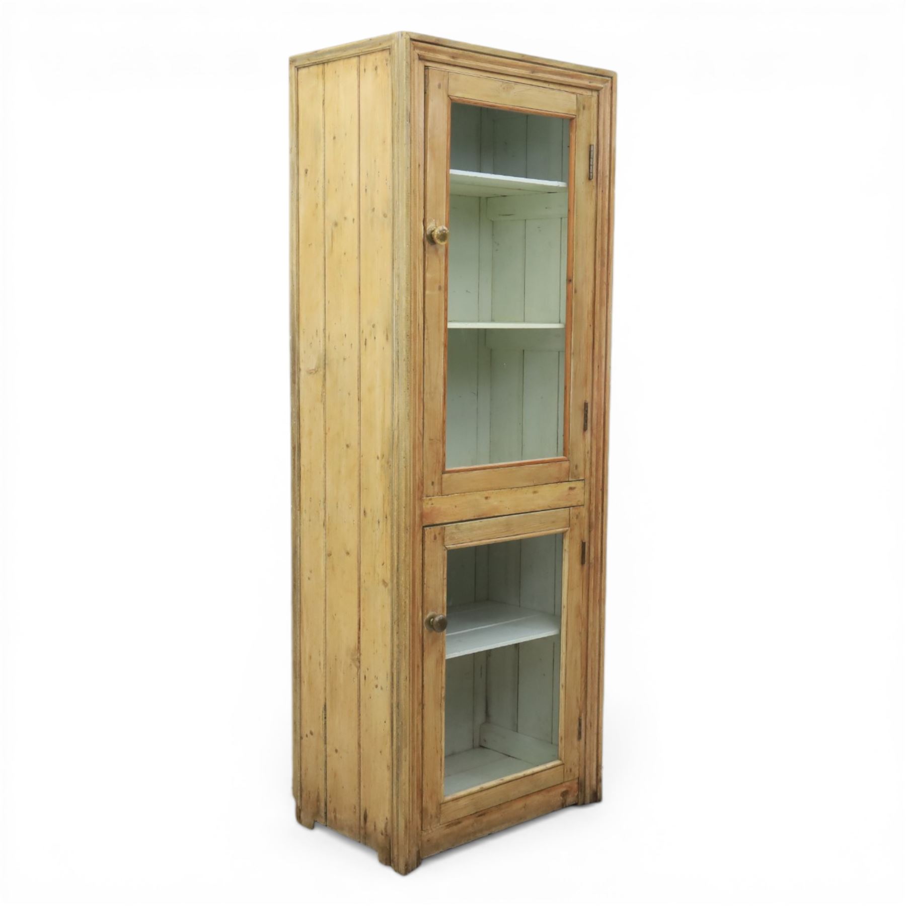 Early 20th century waxed pine kitchen cupboard, rectangular form with moulded top, enclosed by two glazed doors revealing painted interior with shelves, boarded sides and back, fitted with brass knob handles