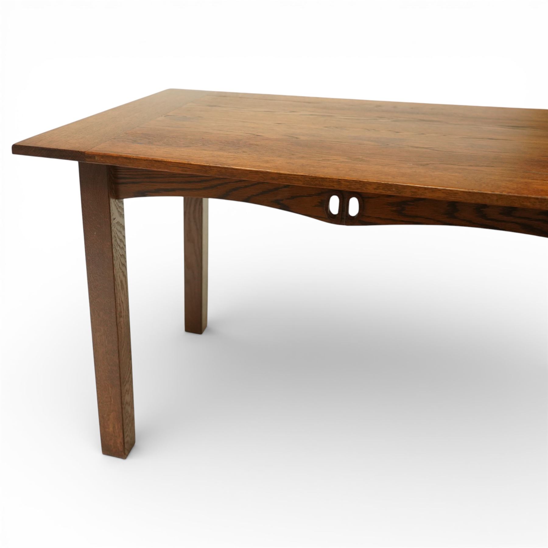 Late 20th century Mackintosh style oak dining table, rectangular top with broad plank surface over shaped frieze with twin pierced oval apertures, raised on square section supports