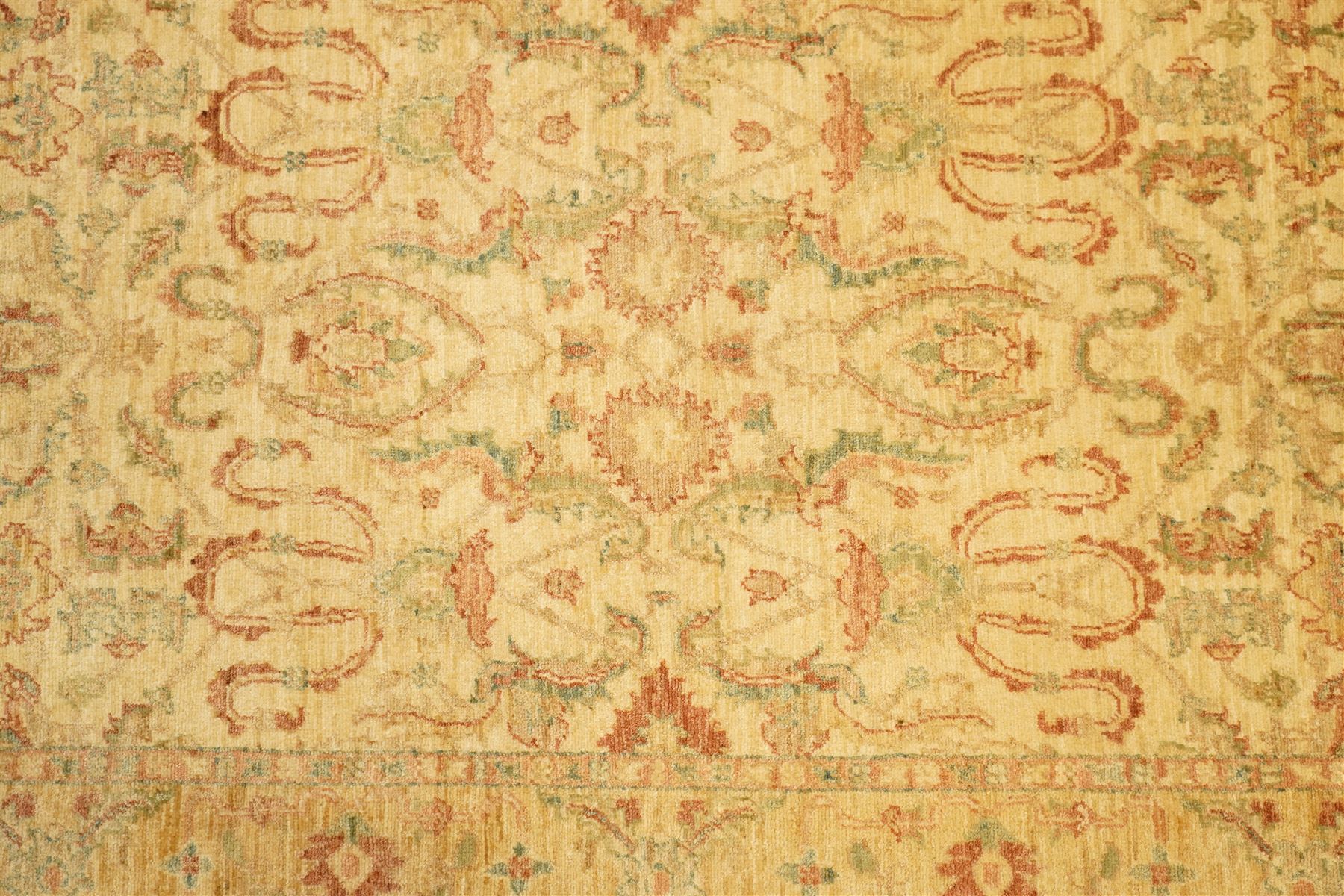 Ziegler design hand-knotted wool rug, the central field with symmetrical scrolling floral motifs in muted tones of beige, sage green, and terracotta, within a conforming border, all on a soft ivory ground