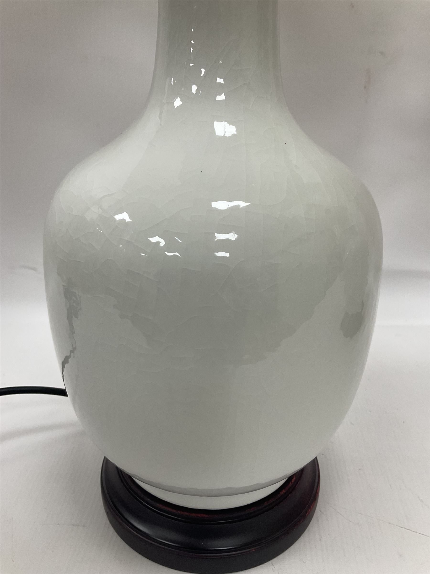 Pair of Chinese ivory crackle glazed table lamps, each of bottle form, raised upon circular hardwood base, excluding fittings H43cm